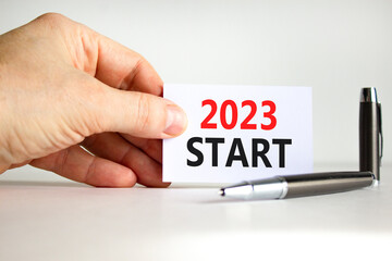 2023 Start symbol. White paper with words 2023 Start. Businessman hand. Metallic pen. Beautiful white table white background. Business and 2023 start concept. Copy space.