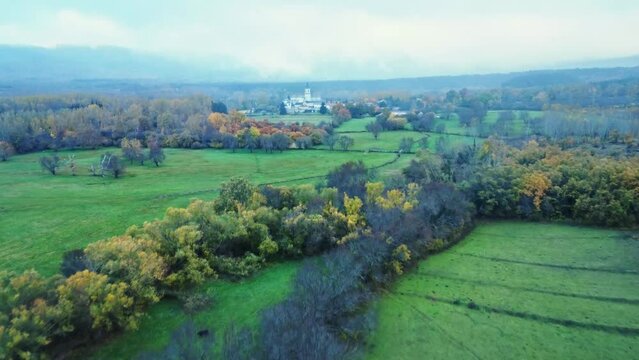 Scenic landscape of town surrounded by colorful autumn trees on cloudy day