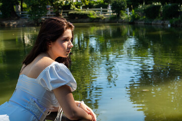 A beautiful girl in a white dress by the lake