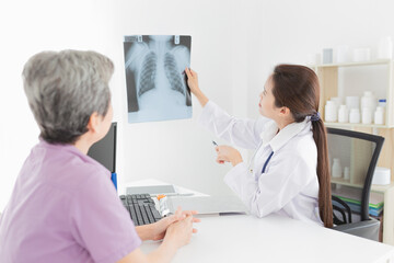 Obraz premium asian doctor looking patient film, he talk about symptoms and treatment plan of patient, he explain about disease with old patient, broken bone treatment, tuberculosis screening