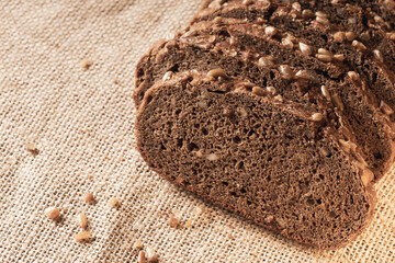 sliced dark flour bread with seeds on a fabric background