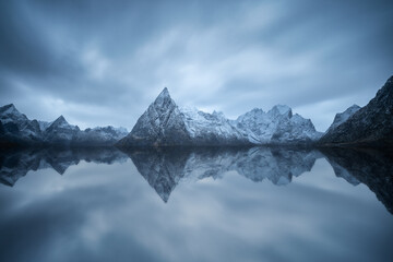 Rocky mountain ridge and wavy sea against gloomy sky in Norway