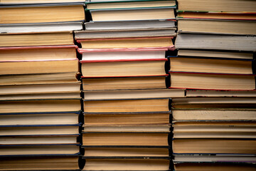 Shelves with old books. Stacks of textbooks with red, blue, green covers and paper sheets with shadow in a dark library. Stacked retro books in a bookstore.