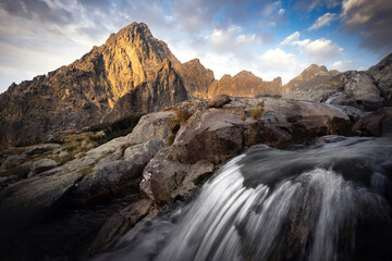 Mountain peaks with a waterfall in the foreground. High Tatras in Slovakia.