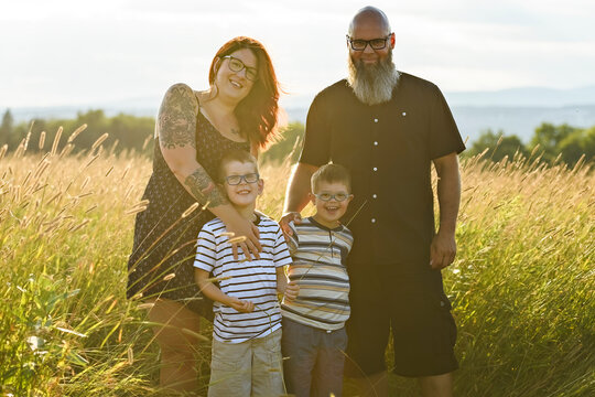 Portrait of a little boy with down syndrome in sunset on summer season with his family