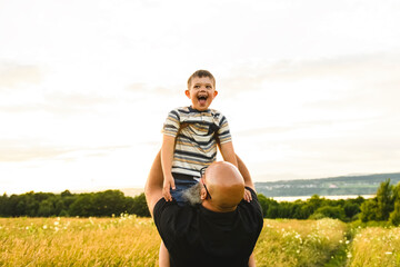 Portrait of a little boy with down syndrome in sunset on summer season with his father