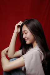 Asian woman taking photo on a red background. Happy Asian woman. Beautiful asian woman with long and straight hair.