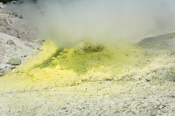 yellow cone of crystallized sulfur around a smoking solfatara on the slope of a volcano