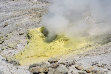 smoking solfatara among sulfur deposits on the slope of the volcano