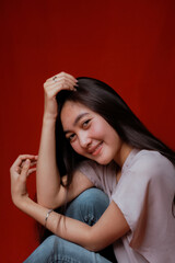 Fototapeta premium Asian woman taking photo on a red background. Happy Asian woman. Beautiful asian woman with long and straight hair.