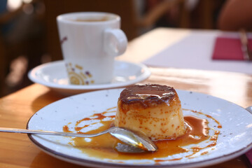  spanish flun pudding dessert close up photo with teaspoon and cup of coffee on the background