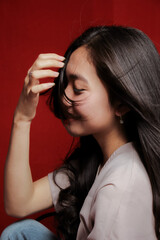 Obraz premium Asian woman taking photo on a red background. Happy Asian woman. Beautiful asian woman with long and straight hair.