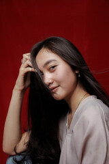 Asian woman taking photo on a red background. Happy Asian woman. Beautiful asian woman with long and straight hair.