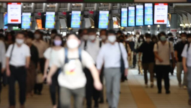 Images (out of focus) of Japanese businessmen and women are commuting while wearing masks during covid-19