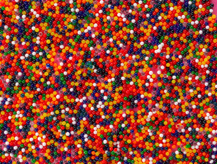 Top view of colored small plastic beads. Bright red, yellow, green, blue and white round balls on a...
