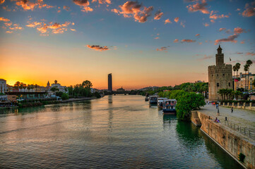 Fototapeta premium Sunset over Seville, Spain, with the Guadalquivir River flowing past the iconic Torre del Oro.
