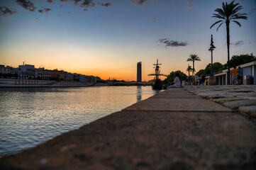 This image showcases the Nao Victoria, a replica of Magellan's ship, docked in the Guadalquivir...