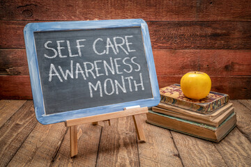 self care awareness month - white chalk writing on a slate blackboard in a retro classroom,...