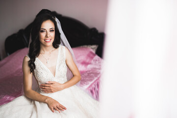 Fototapeta premium Beautiful bride wearing fashion wedding dress with feathers with luxury delight make-up and hairstyle, studio indoor photo shoot