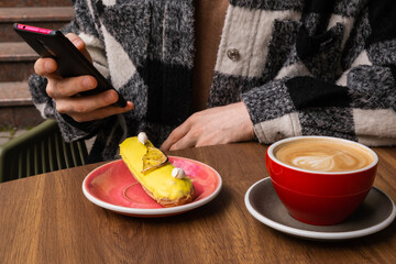 Autumn coffee and desserts close-up. Coffee break outside. Autumn drinks and mood. Flavored coffee. Bright dessert. Eclair. Coffee in male and female hands.