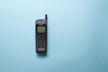 A vintage mobile phone from the 1990s isolated on a blue background. - obrazy, fototapety, plakaty