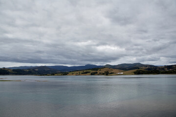 Sea under a cloudy sky with mountains in the background