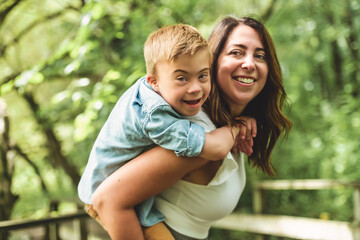 Portrait of a little boy with down syndrome while playing in a park with his mother