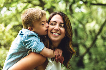 Portrait of a little boy with down syndrome while playing in a park with his mother © Louis-Paul Photo