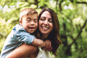 Obraz premium Portrait of a little boy with down syndrome while playing in a park with his mother