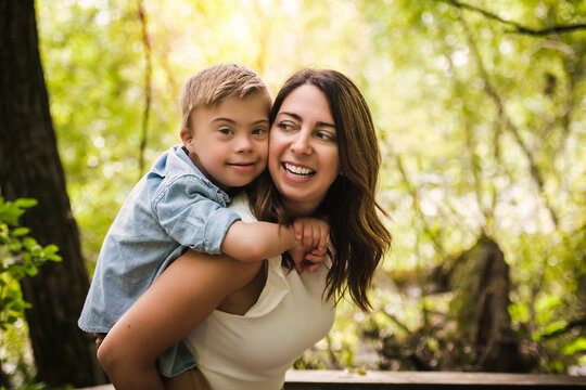Portrait of a little boy with down syndrome while playing in a park with his mother