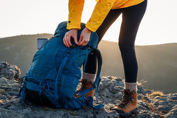 Woman opening backpack after climbing mountain peak. Hiking outdoors