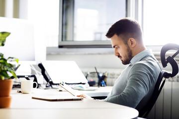 Side view of businessman reading document on clipboard in creative office
