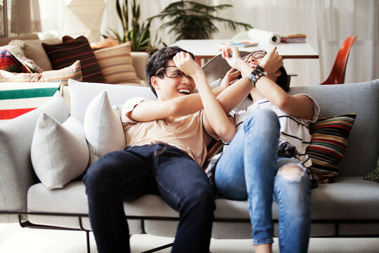 Playful multi-ethnic couple reclining on sofa at home