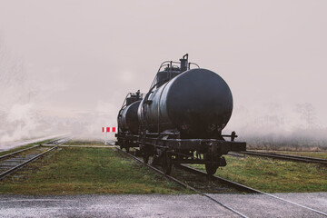 Oil embargo scene of two train tank cars standing behind a dead end traffic sign in front of fog and smoke with copy space - obrazy, fototapety, plakaty