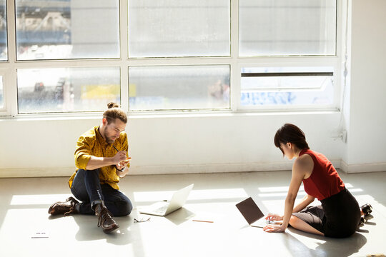High angle view of business people using laptops on floor in creative office
