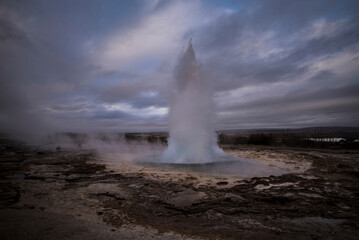 Geyser erupting hot spring against cloudy sky