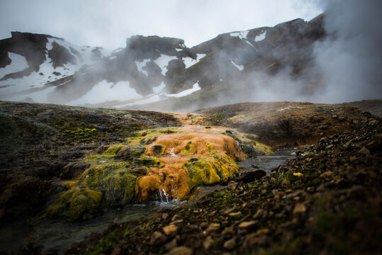 Stream flowing through rocks against snowcapped mountain during winter