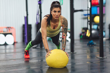 Athlete doing push-ups with medicine ball in gym
