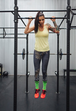 Woman exercising on monkey bars in gym