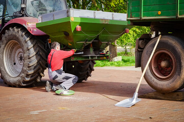 Landwirt kontrolliert seinen Düngerstreuer auf seinen Hof.