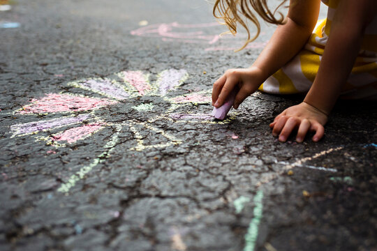 Cropped image of girl drawing flower on road