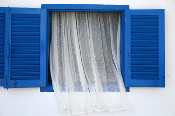 White curtains hanging amidst blue window