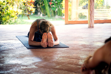 Woman practicing seated forward bend pose in yoga studio