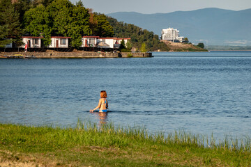 Young woman walking in the lake near the beach in the summer resort