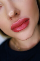 Fototapeta premium close-up of the lips of a beautiful girl model with the work done on the permanent make-up of the lips