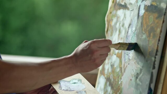 Close-up of an artist's hands painting a picture with a brush. A man draws and looks for inspiration in nature. High quality 4k footage