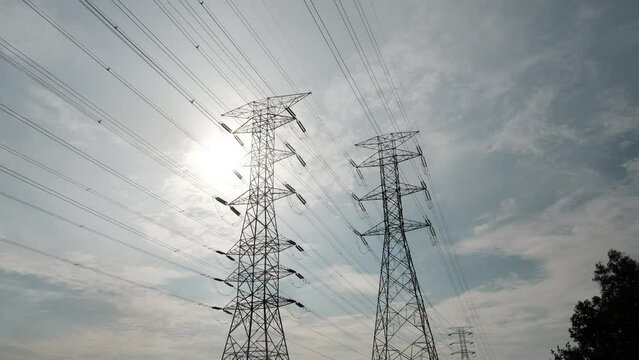 A timelapse footage with noise effect electic transmission tower with moving cloud and sun insight. Electric and energy concept.