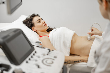 Woman during an ultrasound examination of the abdominal cavity at modern medical office. Concept of...