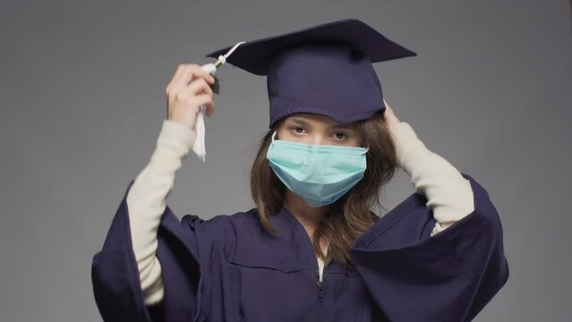 Graduation girl putting on cap. Female student wearing protective face mask..