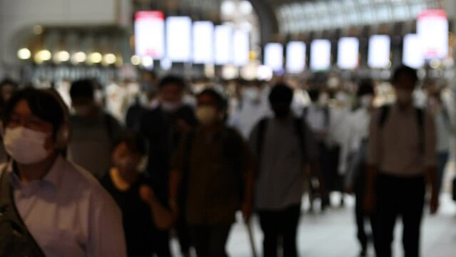 Images (out of focus) of Japanese businessmen and women are commuting while wearing masks during covid-19